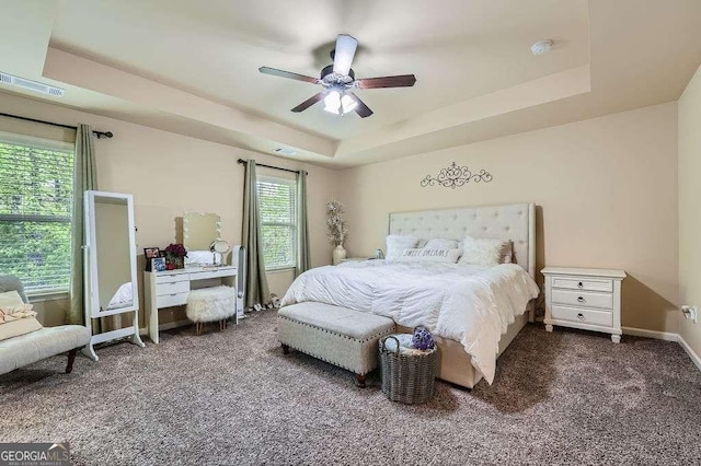 bedroom featuring baseboards, a raised ceiling, visible vents, ceiling fan, and carpet