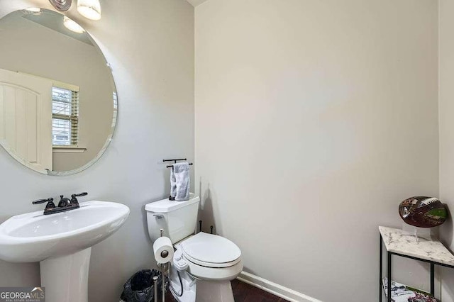 bathroom with toilet, a sink, and baseboards