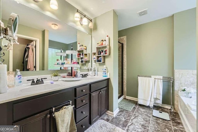 full bath with a shower stall, double vanity, a sink, and visible vents