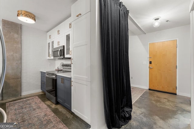 245 N Highland Ave NE Unit 220, Atlanta, GA 30307 - kitchen featuring stainless steel appliances, finished concrete floors, white cabinets, light countertops, and baseboards