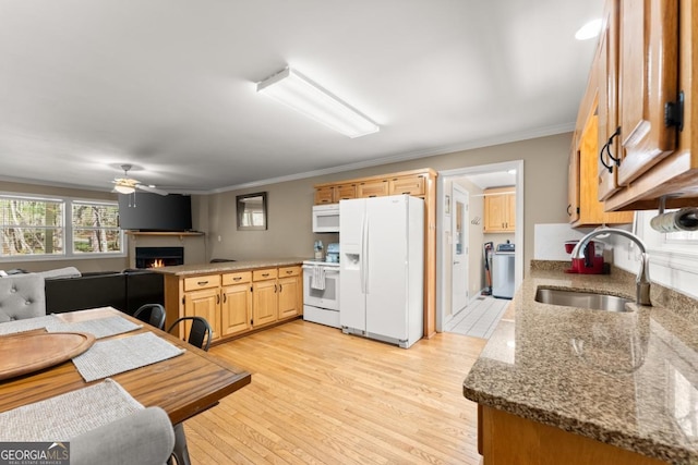 kitchen featuring white appliances, a sink, ceiling fan, a warm lit fireplace, and crown molding