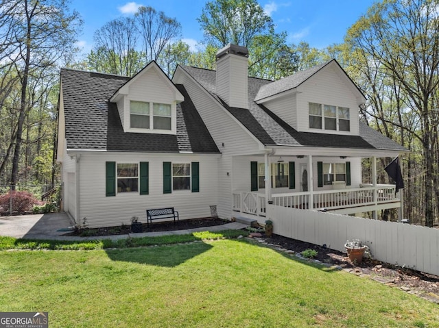 back of property featuring covered porch, a chimney, roof with shingles, and a yard