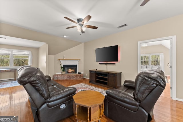 living area with ceiling fan, plenty of natural light, vaulted ceiling, and wood finished floors
