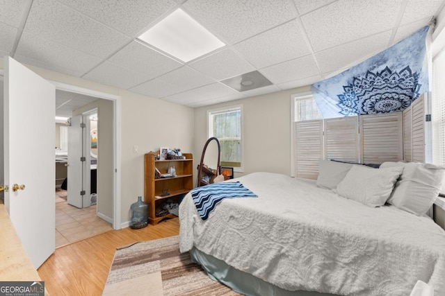 bedroom with a drop ceiling and wood finished floors