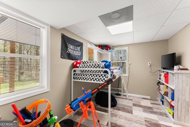 bedroom featuring a paneled ceiling, multiple windows, and baseboards