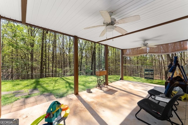 view of patio / terrace featuring a ceiling fan and a forest view