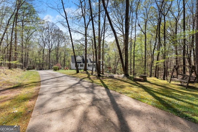 view of home's community with a yard, a wooded view, and driveway
