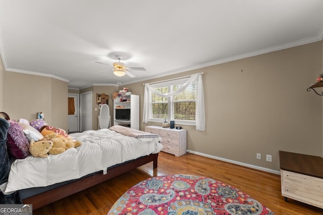 bedroom featuring wood finished floors, crown molding, baseboards, and a ceiling fan