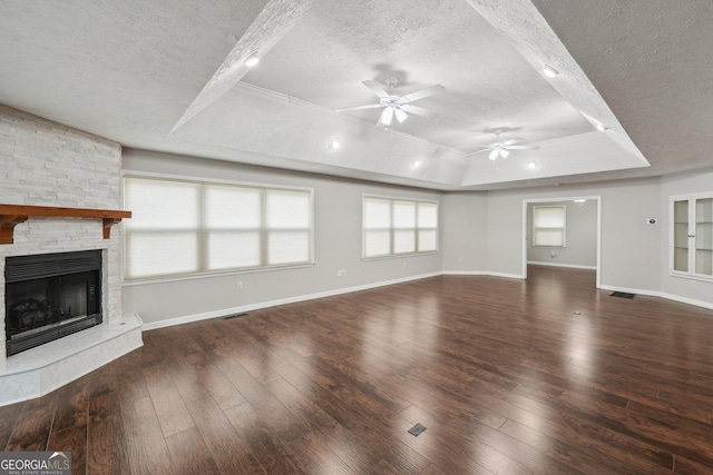 unfurnished living room with a raised ceiling, a textured ceiling, ceiling fan, and wood-type flooring