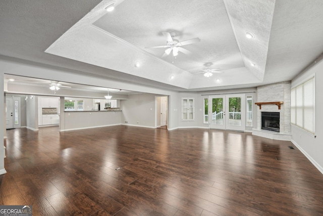 unfurnished living room with a raised ceiling, a textured ceiling, and ceiling fan