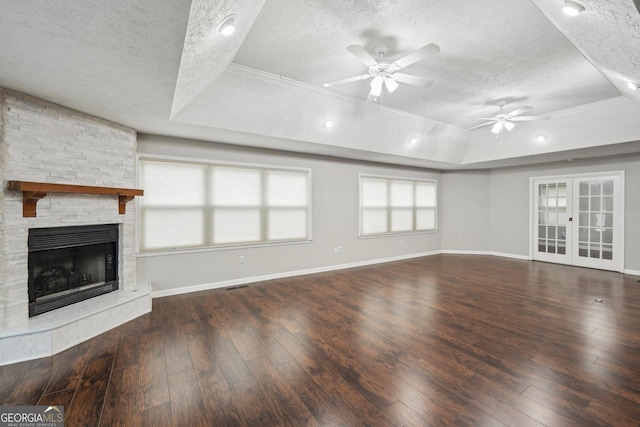 unfurnished living room featuring a textured ceiling, a ceiling fan, ornamental molding, and a raised ceiling