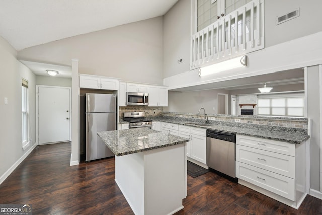 kitchen featuring high vaulted ceiling, white cabinetry, a sink, and appliances with stainless steel finishes