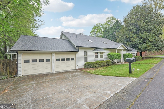 view of front facade with a front yard, concrete driveway, a garage, and roof with shingles