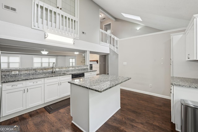 kitchen featuring light stone counters, white cabinets, visible vents, high vaulted ceiling, and a sink
