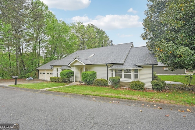 view of front of house featuring aphalt driveway, an attached garage, a front lawn, and a shingled roof