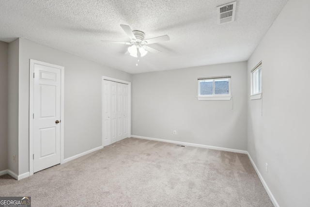 unfurnished bedroom featuring a closet, baseboards, a textured ceiling, visible vents, and carpet
