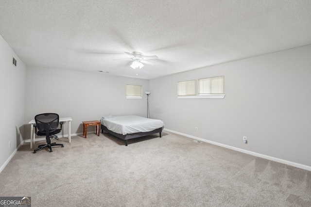 carpeted bedroom featuring visible vents, a textured ceiling, baseboards, and ceiling fan