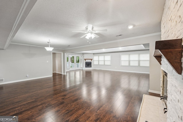 unfurnished living room with dark wood finished floors, a stone fireplace, crown molding, and ceiling fan