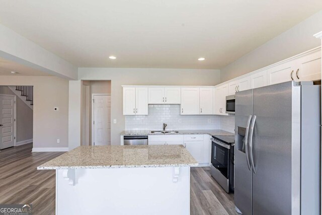 417 Flowery Branch Ct, Villa Rica, GA 30180 - kitchen with appliances with stainless steel finishes, a center island, decorative backsplash, a sink, and wood finished floors