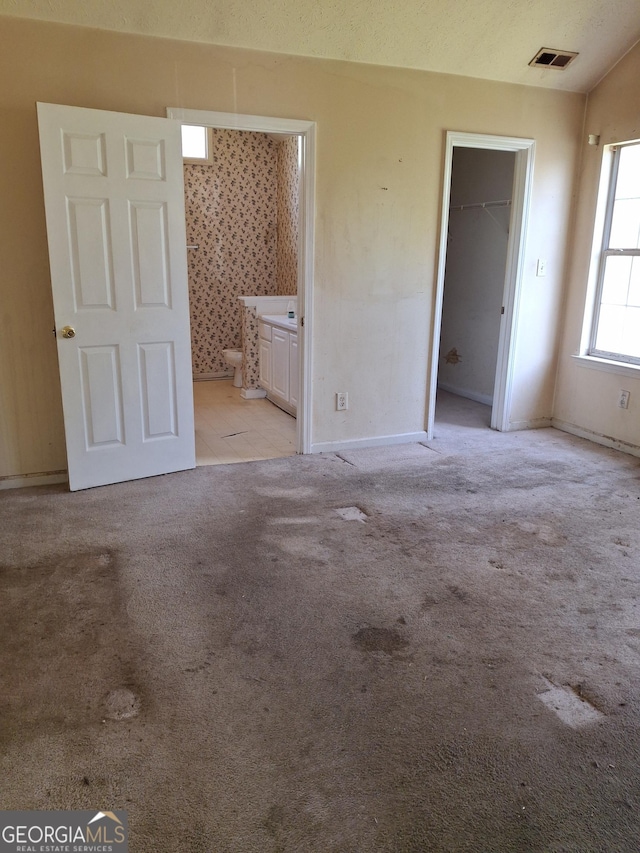 172 Willow Springs Ln, Stockbridge, GA 30281 - unfurnished bedroom with light carpet, a walk in closet, a closet, and connected bathroom