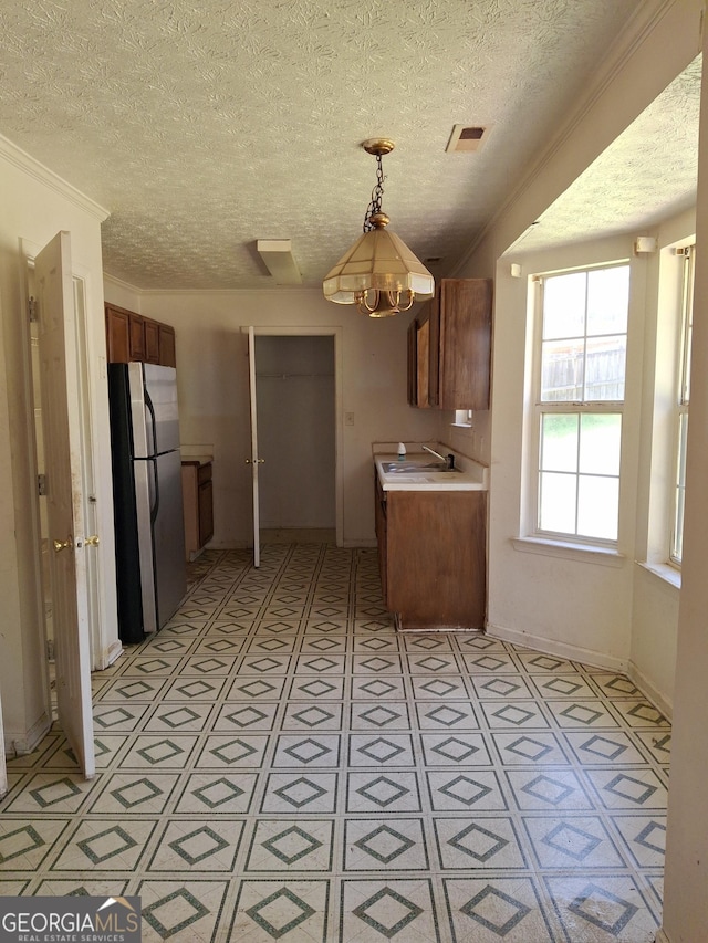172 Willow Springs Ln, Stockbridge, GA 30281 - kitchen with freestanding refrigerator, a textured ceiling, light floors, brown cabinets, and light countertops