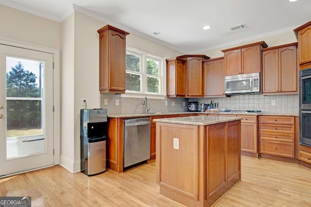 5177 Cabot Creek Dr, Buford, GA 30518 - kitchen with appliances with stainless steel finishes, light wood finished floors, light stone countertops, a center island, and crown molding