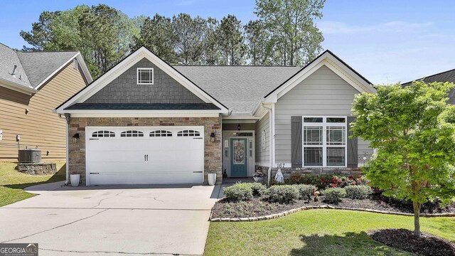 craftsman inspired home featuring a garage, central air condition unit, stone siding, a front lawn, and driveway
