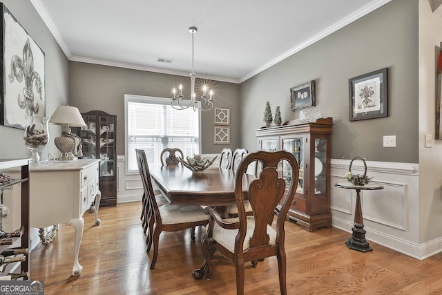dining room featuring crown molding, visible vents, light wood finished floors, and an inviting chandelier