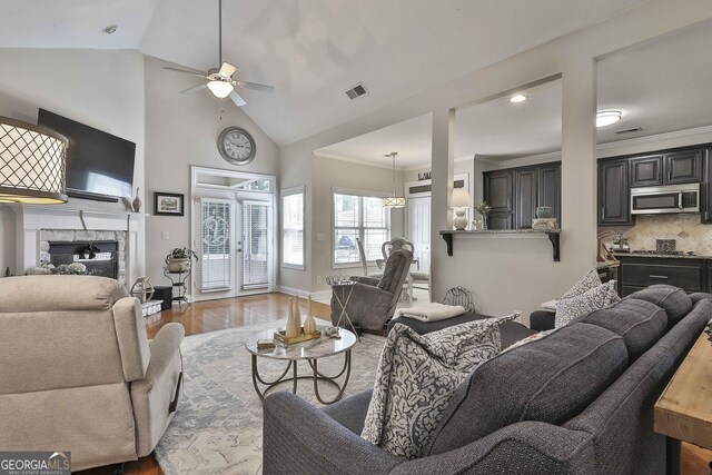 living area featuring crown molding, wood finished floors, ceiling fan, and a tile fireplace