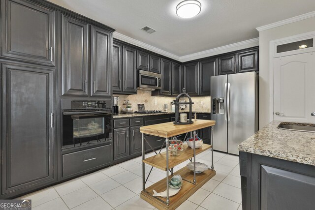 kitchen with light tile patterned floors, backsplash, crown molding, visible vents, and appliances with stainless steel finishes