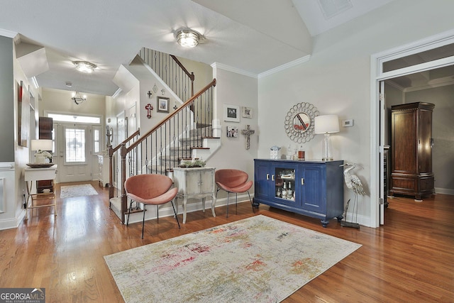 entryway with visible vents, baseboards, ornamental molding, wood finished floors, and stairs
