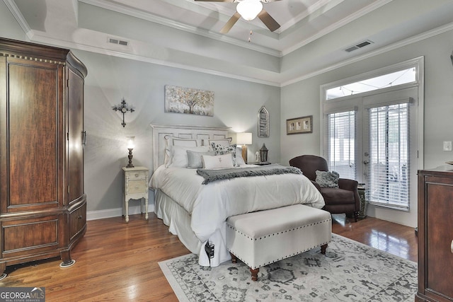 bedroom featuring visible vents, access to exterior, wood finished floors, and a raised ceiling
