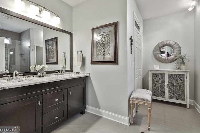 full bath featuring a shower stall, a sink, tile patterned floors, double vanity, and baseboards