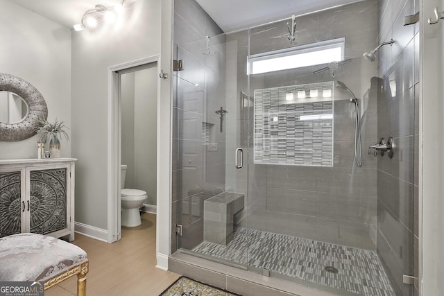 bathroom featuring toilet, baseboards, and a stall shower