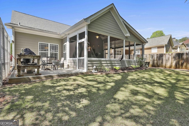 back of house featuring a sunroom, a yard, a fireplace, fence, and a patio