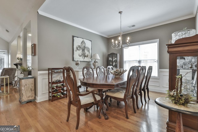 dining space featuring light wood finished floors, visible vents, an inviting chandelier, and ornamental molding