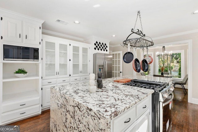 kitchen with stainless steel appliances, a chandelier, light stone countertops, ornamental molding, and a kitchen island