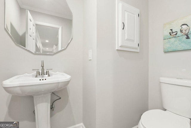 bathroom featuring toilet, baseboards, and a sink