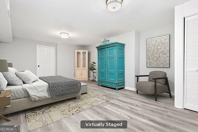 bedroom featuring wood finished floors, baseboards, and a closet