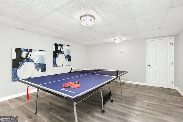 recreation room with wood finished floors, a drop ceiling, and baseboards