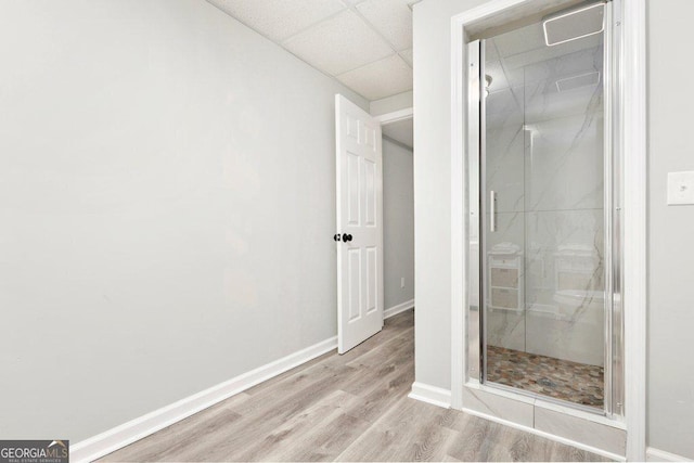 bathroom with wood finished floors, baseboards, and a paneled ceiling