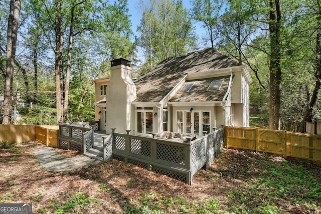 back of house with french doors, a deck, a fenced backyard, and a chimney