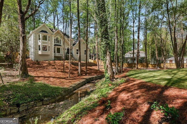 view of yard featuring fence and view of wooded area