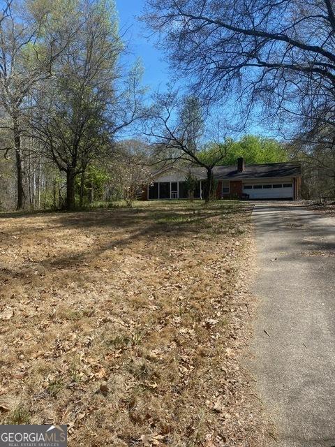 view of front facade with an attached garage, a chimney, and aphalt driveway
