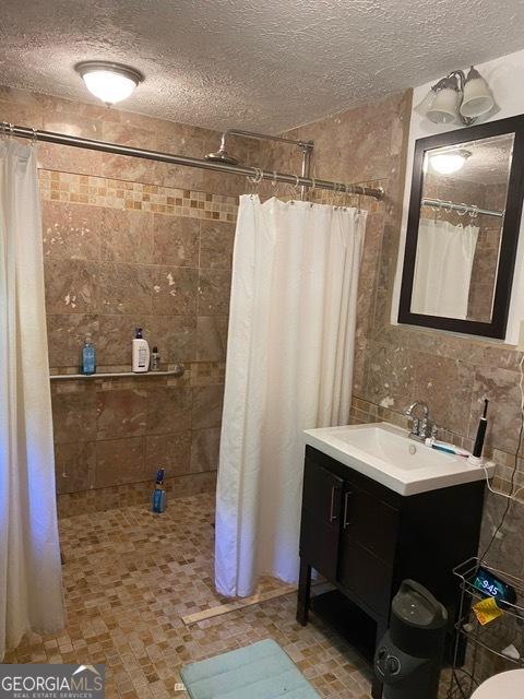 bathroom with tiled shower, vanity, and a textured ceiling