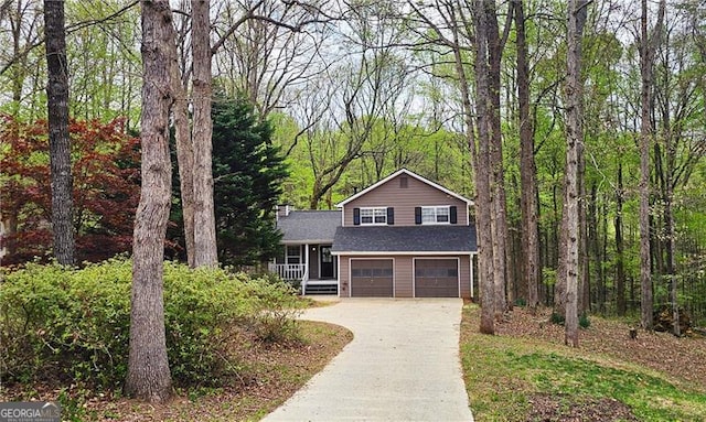 split level home with a view of trees, concrete driveway, and a garage