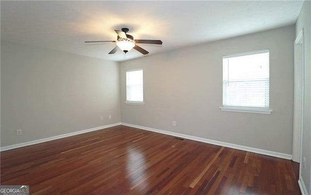 empty room featuring dark wood-type flooring, baseboards, and a ceiling fan