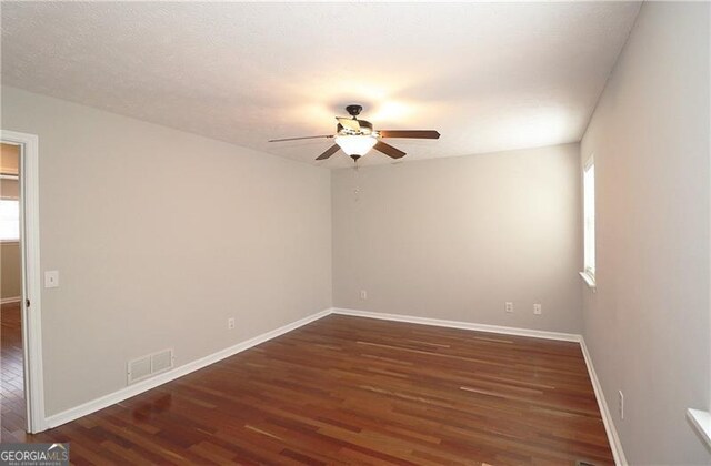 unfurnished room with visible vents, baseboards, wood finished floors, and ceiling fan
