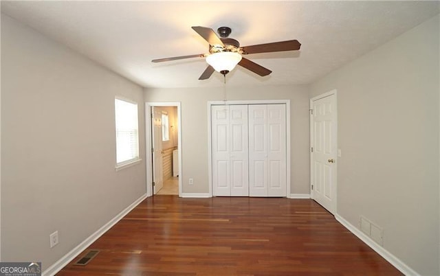 unfurnished bedroom featuring visible vents, baseboards, a closet, and wood finished floors