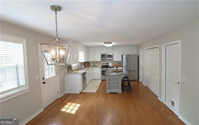 kitchen featuring an inviting chandelier, a sink, light countertops, stainless steel appliances, and light wood-style flooring